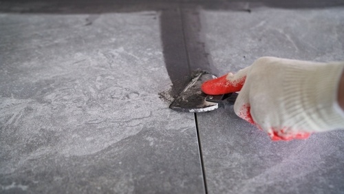 Applying grout to floor tiles with a tool | Ultratech