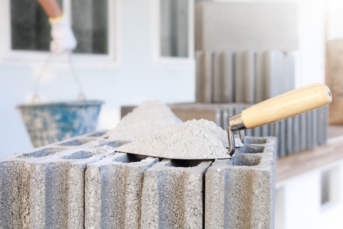 Cement or mortar, Cement powder with a trowel put on the brick for construction work and there are construction workers in the background.