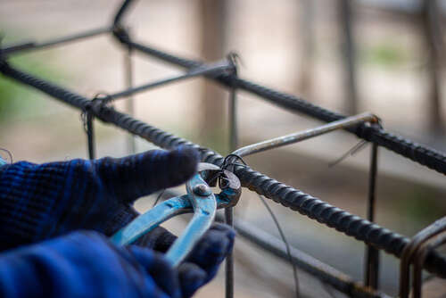 The hands of construction workers using steel wire to bind steel bars.