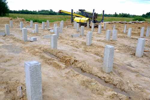 A pile driving mechanism operating on a construction site.Concrete piles or pillars are dug into the ground. The construction of a monolithic building or bridge has begun.Development of the district