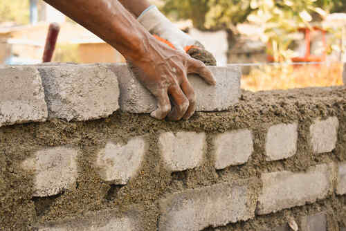 manual worker building bricks wall