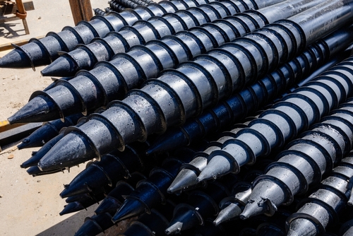 Steel helical screw piles for house foundation construction and deep foundation support.