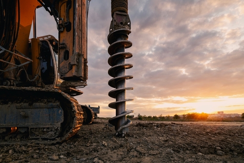 Helical auger drilling machine used for foundation piling and soil excavation on a construction site.