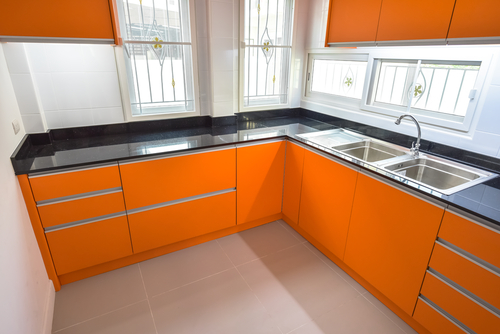 Bright orange kitchen cabinets with a black counter and a double sink | Ultratech