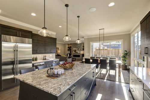 Modern gray kitchen with dark cabinets, granite island, pendant lights, and dining area.