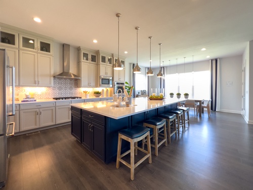Modern kitchen with a large island, pendant lights, and white cabinets with dark lower cabinets
