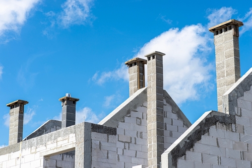 The gable walls are poured with concrete, with visible system chimneys.