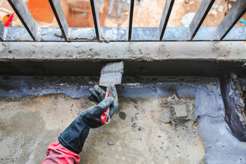 Waterproofing membrane applied around a concrete foundation beneath a metal floor grate
