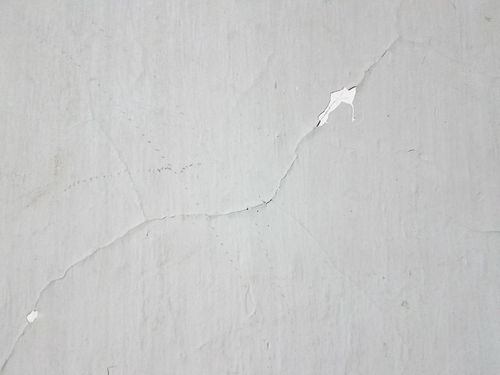 Diagonal cracks and peeling paint on a white wall | Ultratech
