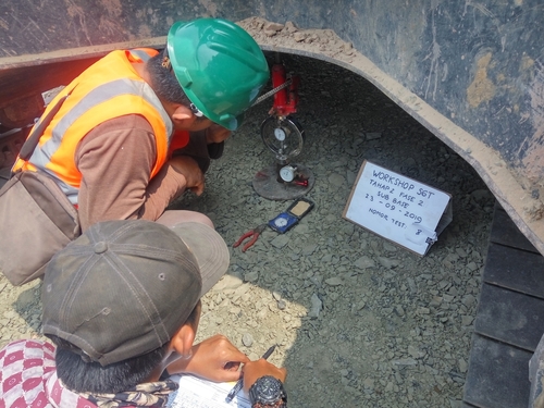 Worker inspecting aggregate material during a construction site quality test