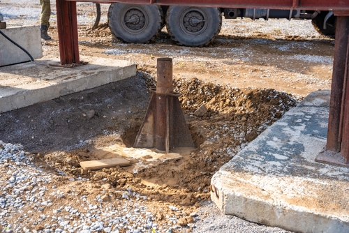 Steel support jack installed in excavated soil beneath a construction structure