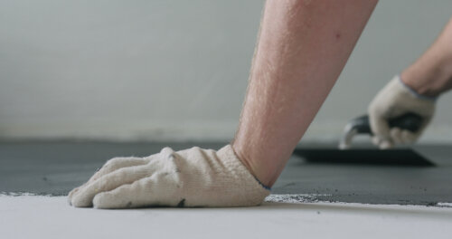 closeup male worker applying micro concrete plaster coating on the floor with a trowel