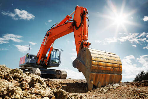 Crawler excavator front view digging on demolition site in backlight