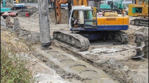 Construction site par zameen me gaddhe karti hui badi machine