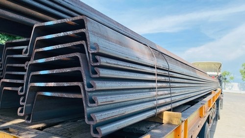 Construction ke liye truck par ladhe hue lambe steel ke sheet piles