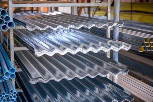 Chhat par lagane wali metal tin sheets aur plastic pipes rack me rakhe hue