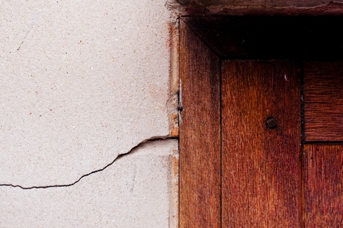 Crack in a concrete wall next to a wooden door | Ultratech