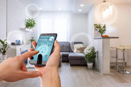 Smart home technology interface on smartphone app screen with augmented reality (AR) view of internet of things (IOT) connected objects in the apartment interior, person holding device