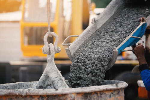 Industrial construction machinery workers pouring cement concrete using a concrete bucket