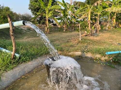 Agriculture blue pipe with groundwater gushing in pond-mixed agricultural garden in Thailand