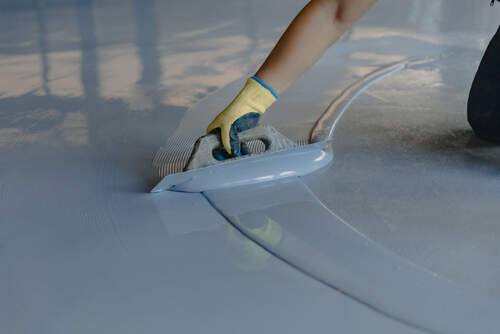 The worker applies gray epoxy resin to the new floor