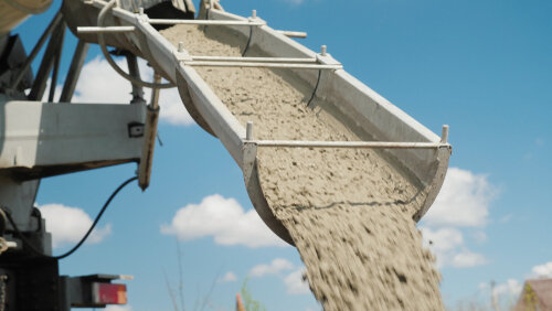 The concrete is unloaded from the concrete mixer. Against the blue sky. Construction of country houses.